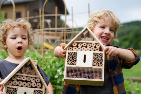 Dos niños sujetando un hotel de insectos cada uno