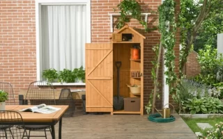 Armario de madera natural tipo cobertizo con puerta abierta junto a una terraza con mesa y sillas