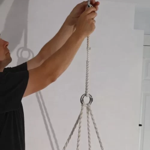 A pendurar a cadeira de rede no ponto de fixação do teto antes de a testar.