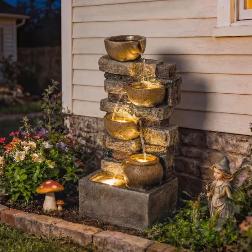 Fonte em cascata com vasos iluminados e uma fada.