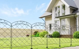 Hilera de paneles de valla decorativos de metal negro con motivo de arco delante de una casa