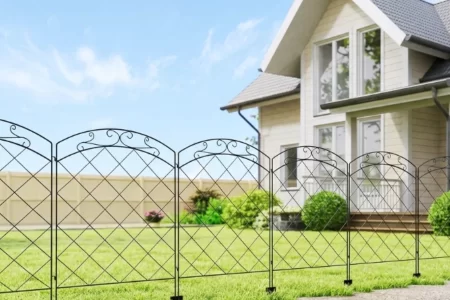 Hilera de paneles de valla decorativos de metal negro con motivo de arco delante de una casa