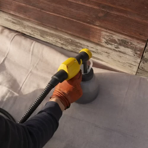 Utilizar uma pistola de pintura com arnês para pintar o abrigo de jardim