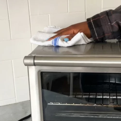 Limpeza da superfície exterior em aço inoxidável do forno de bancada.