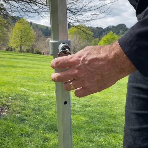 Pessoa a soltar o pino de ajuste de altura da perna de uma tenda gazebo
