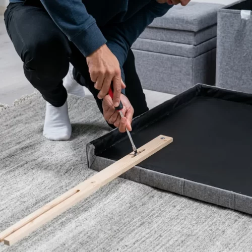 Hombre atornillando una pata de madera a la base del c