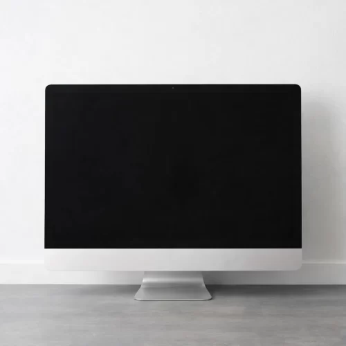 Monitor desligado sobre uma secretária junto a uma parede.